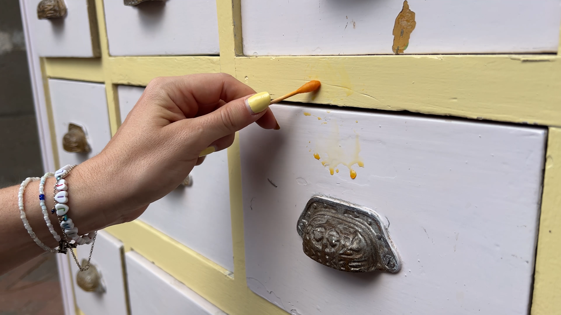 Bij het uit elkaar halen van de kast kwam ik laag na laag tegen: geel, grijs, groen en zelfs rood. Het vergde meerdere lagen afbijtmiddel en eindeloos veel schrapen. Het voelde alsof ik mijn geld verloren had aan een nep-antik.
Maar bij de laden gebeurde er iets bijzonders… De kast was eerder omgebouwd tot een lollypop-stand en zat vol met toevoegingen. Eerst haalde ik alle losse delen, felle verf en MDF-platen weg. Let altijd op bij dit soort projecten: vaak zijn originele elementen verborgen onder latere toevoegingen.